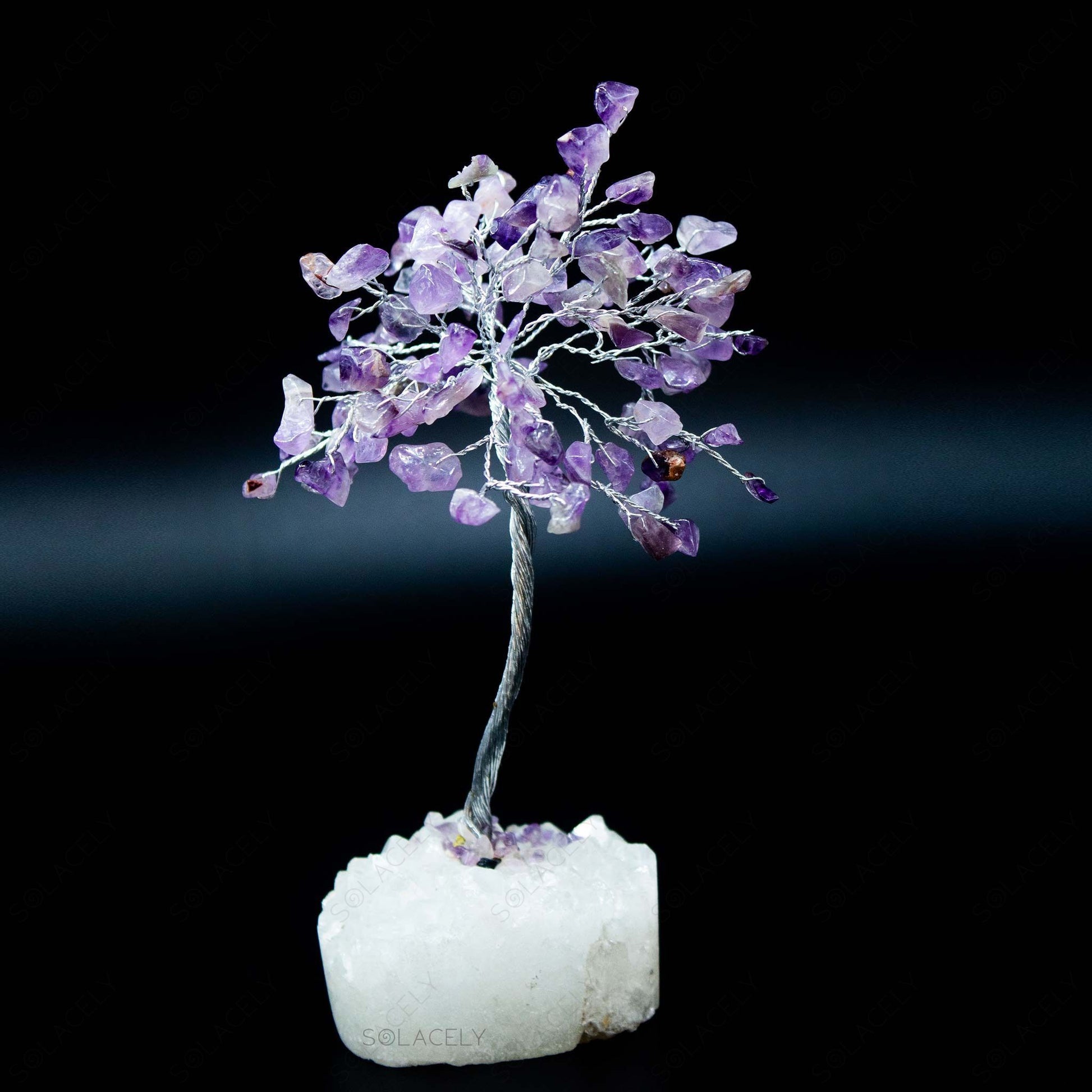 amethyst tree sculpture resting on clear quartz cluster